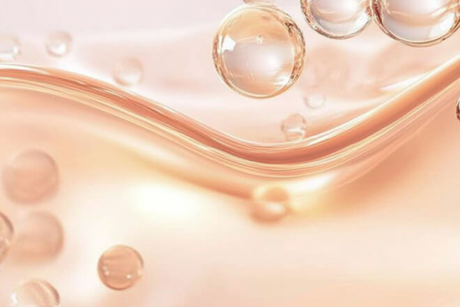 Abstract view of light-pink liquid waves and suspended nutrient-like droplets, evoking absorption and fluid dynamics