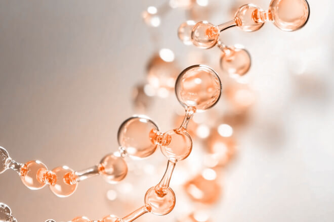 Close-up of a stylized chain of clear orange glass-like molecules, illustrating connectivity or compound formation
